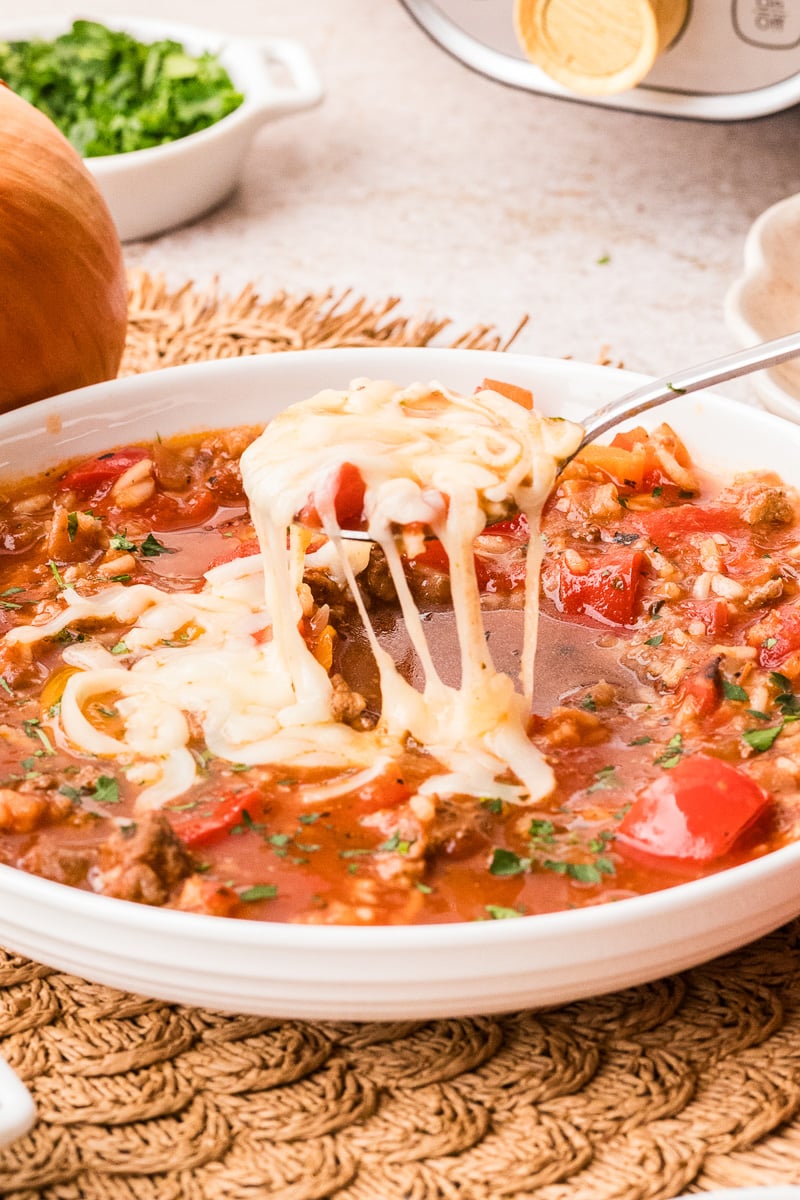 Spoonful of stuffed pepper soup held above bowl of soup.