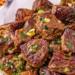 Garlic butter steak bites on white plate.