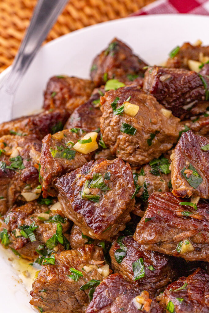 Garlic butter steak bites on white plate.
