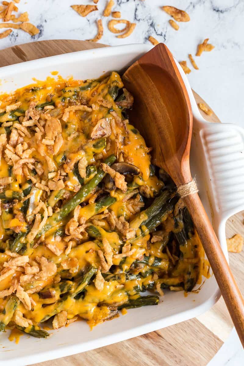 Overhead view of green bean casserole in baking dish with wooden spoon.