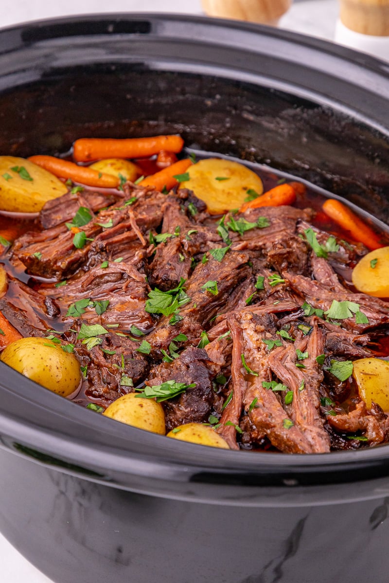 Side view of slow cooker pot roast in slow cooker, ready to be served for dinner.