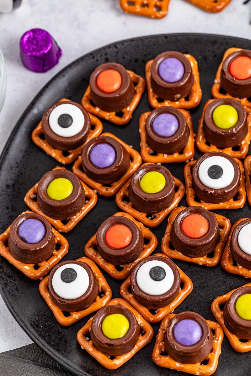 Monster eyeball pretzel bites served on a black plate.