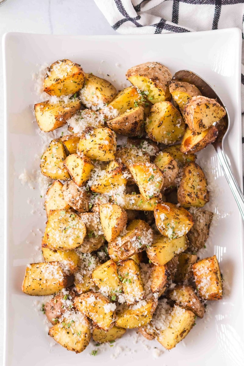 Crispy roasted red potatoes served ona platter with a sprinkle of Parmesan cheese.