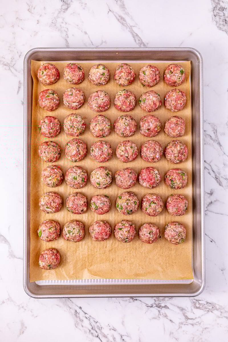 Uncooked meatballs on baking sheet.