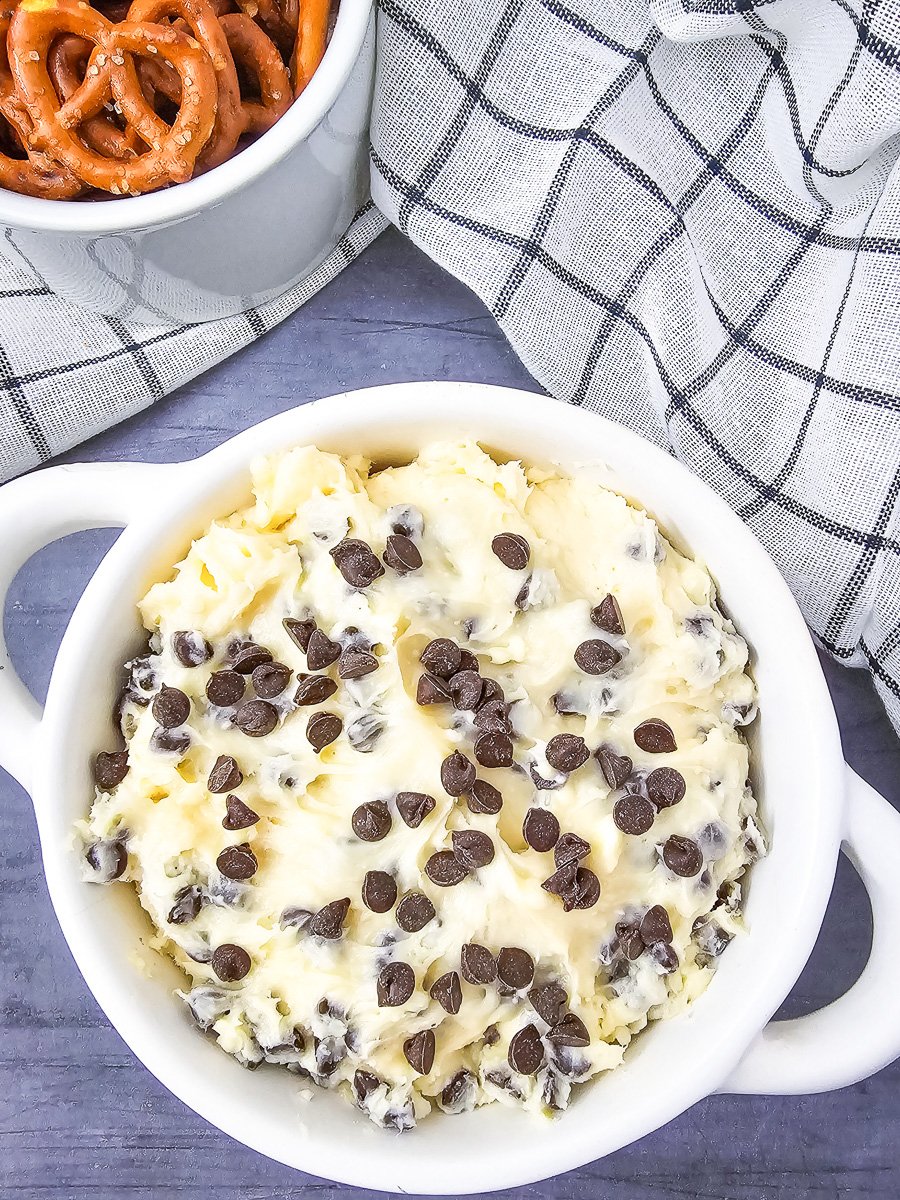Chocolate chip dip with cream cheese in a white bowl with pretzels on the side.