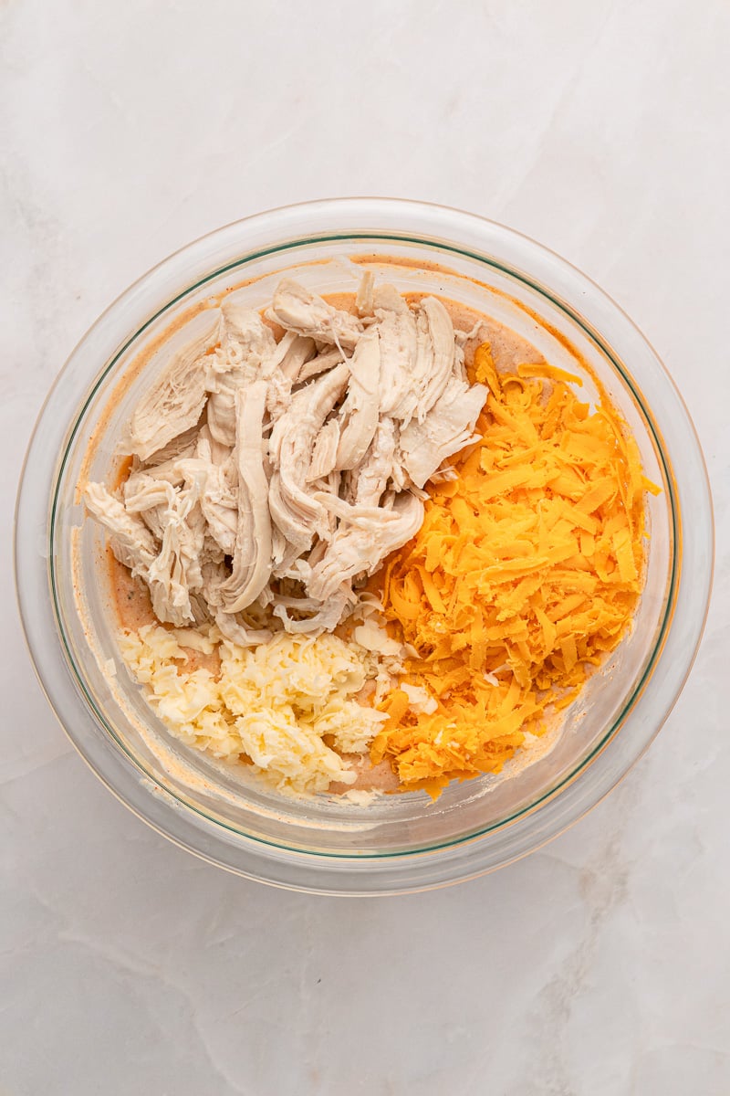 Chicken and shredded cheese are folded into the cheese mixture in small bowl.