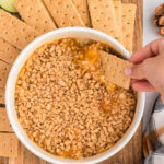 Graham cracker is dipped into caramel apple dip.