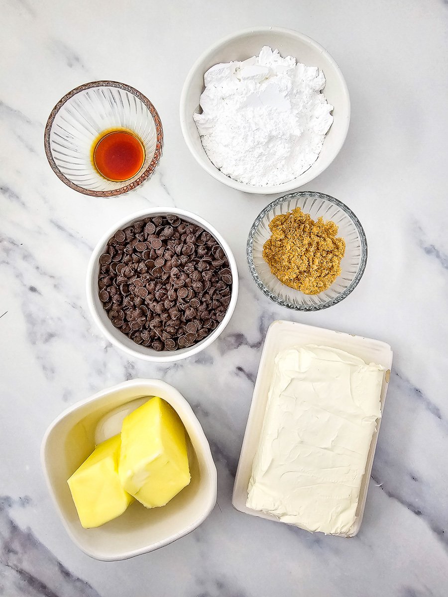 Ingredients for chocolate chip dip laid out in small bowls on kitchen counter.