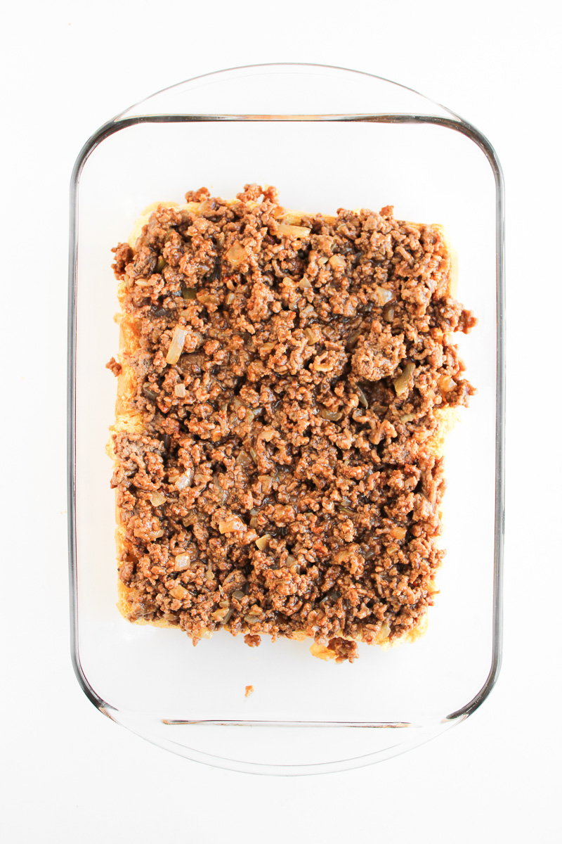 Ground beef mixture in bottom of baking dish on top of slider bottoms.