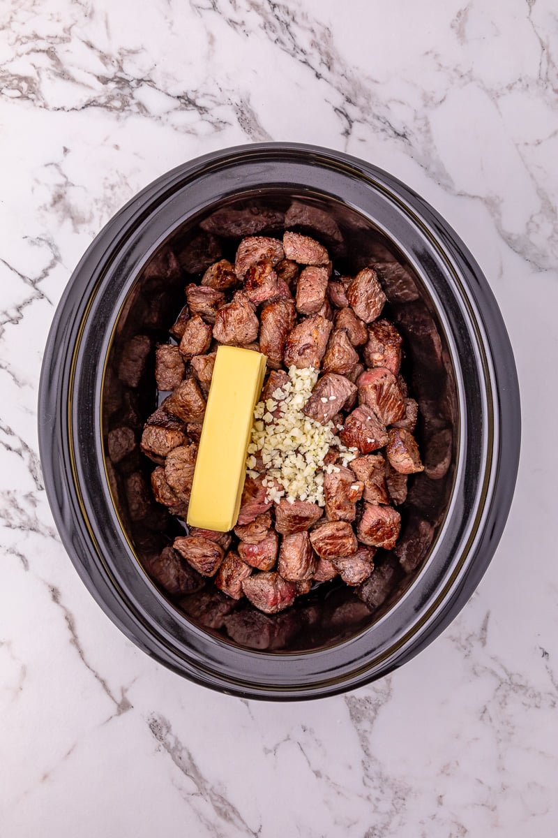 Steak bites, garlic and butter in slow cooker.