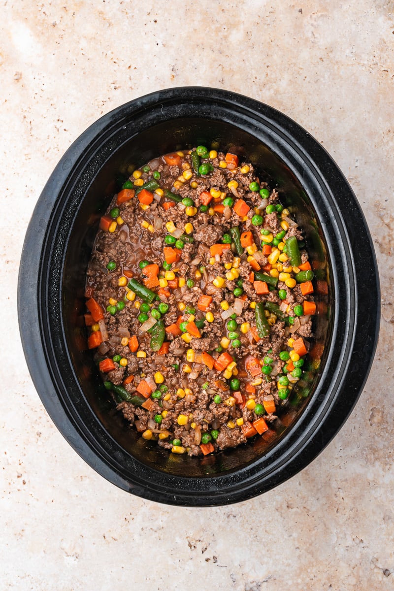 Frozen veggies are added to the bottom of the crockpot.