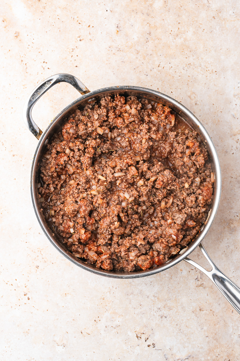 Tomato sauce and other ingredients are added to the skillet.