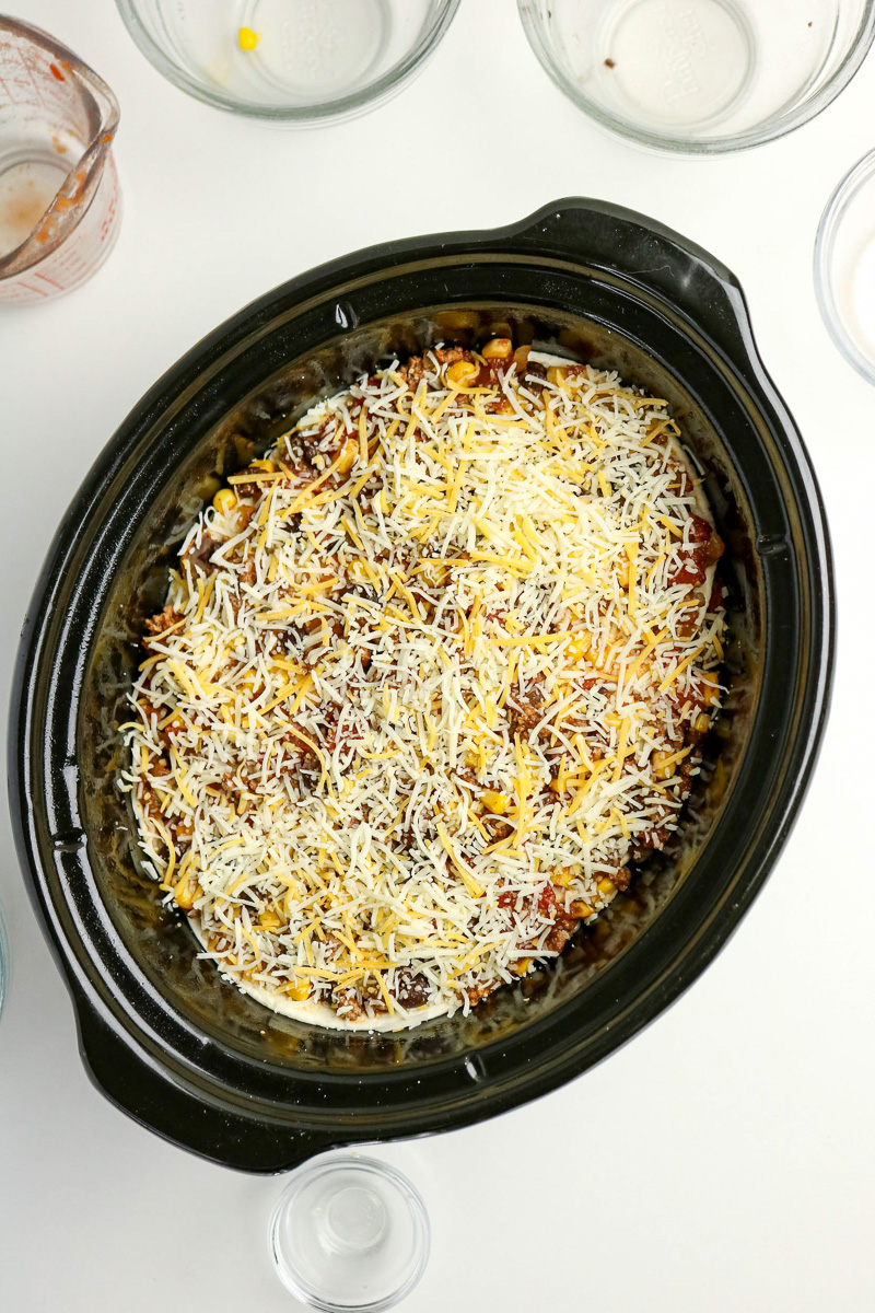 Full layered taco casserole ready to slow cook.