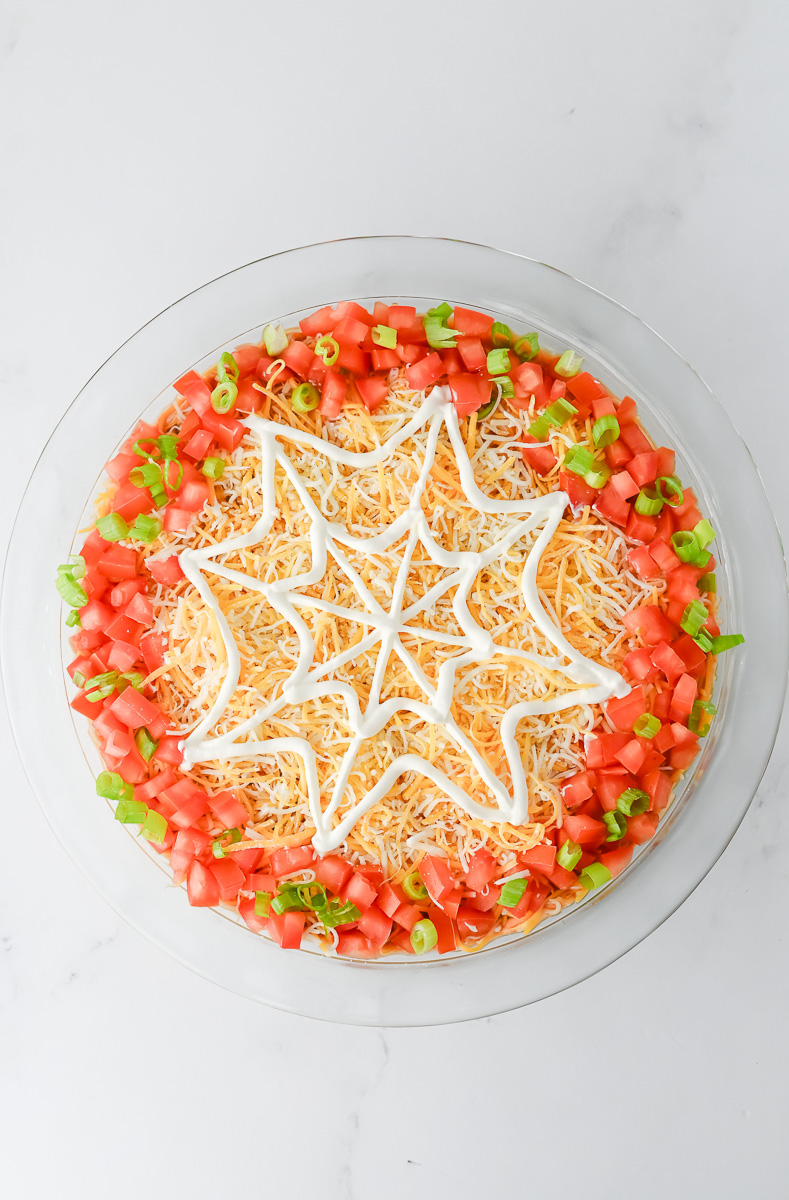 Spider web is drawn on top of the shredded cheese.
