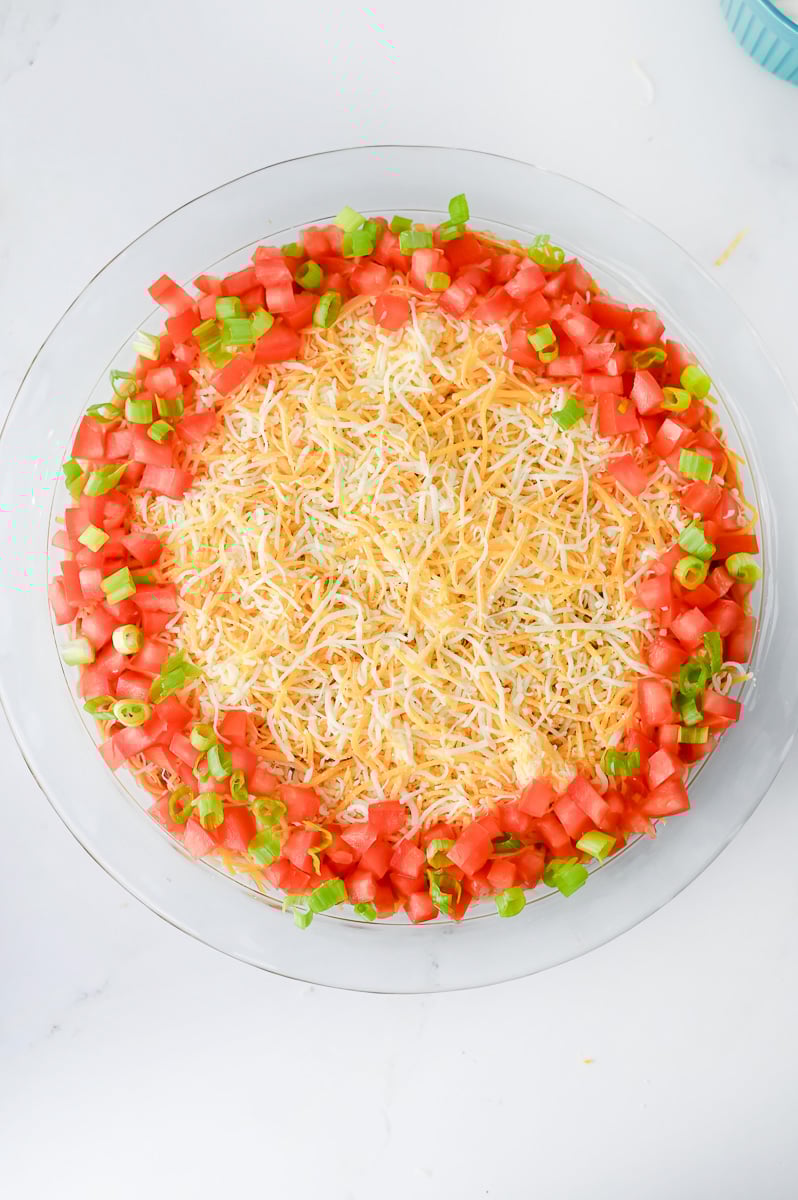 Roma tomato and onions are sprinkled around the edge of the pie plate.