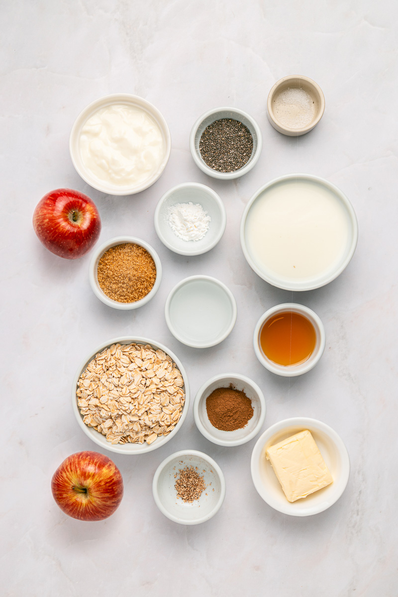 Ingredients for apple pie overnight oats laid out in small bowls on counter in preparation for the recipe.