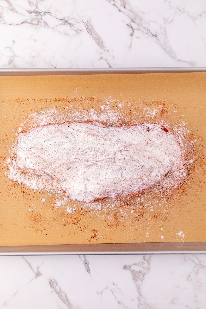 Seasonings are spread on pot roast.