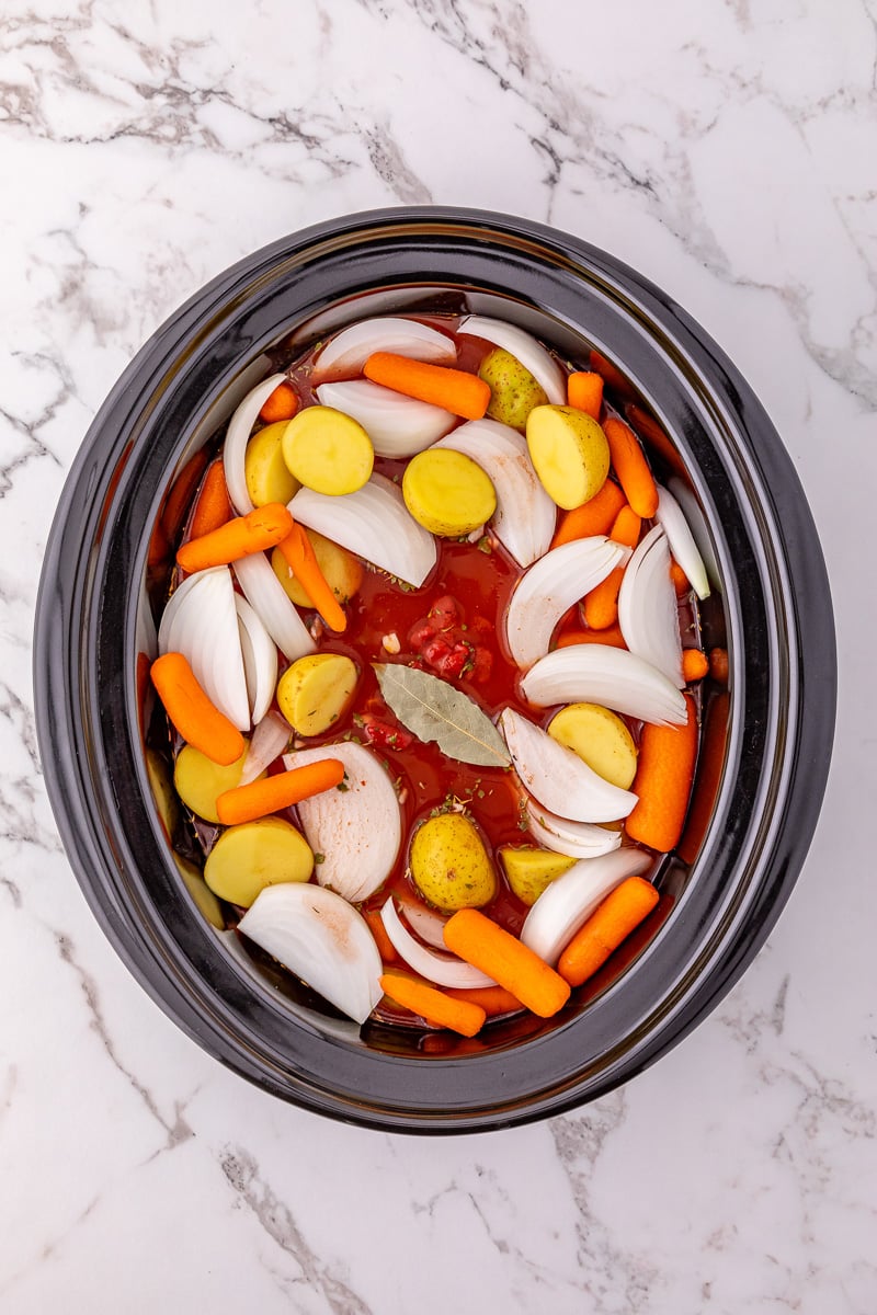 Potatoes and onion are placed surrounding pot roast.