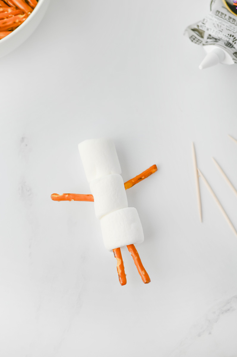 Pretzels are inserted into the marshmallows for arms and legs.