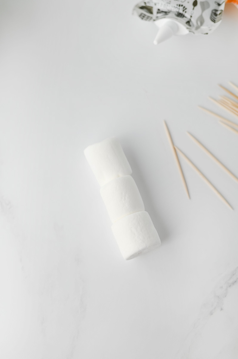 Three marshmallows are stacked and held together with toothpicks.