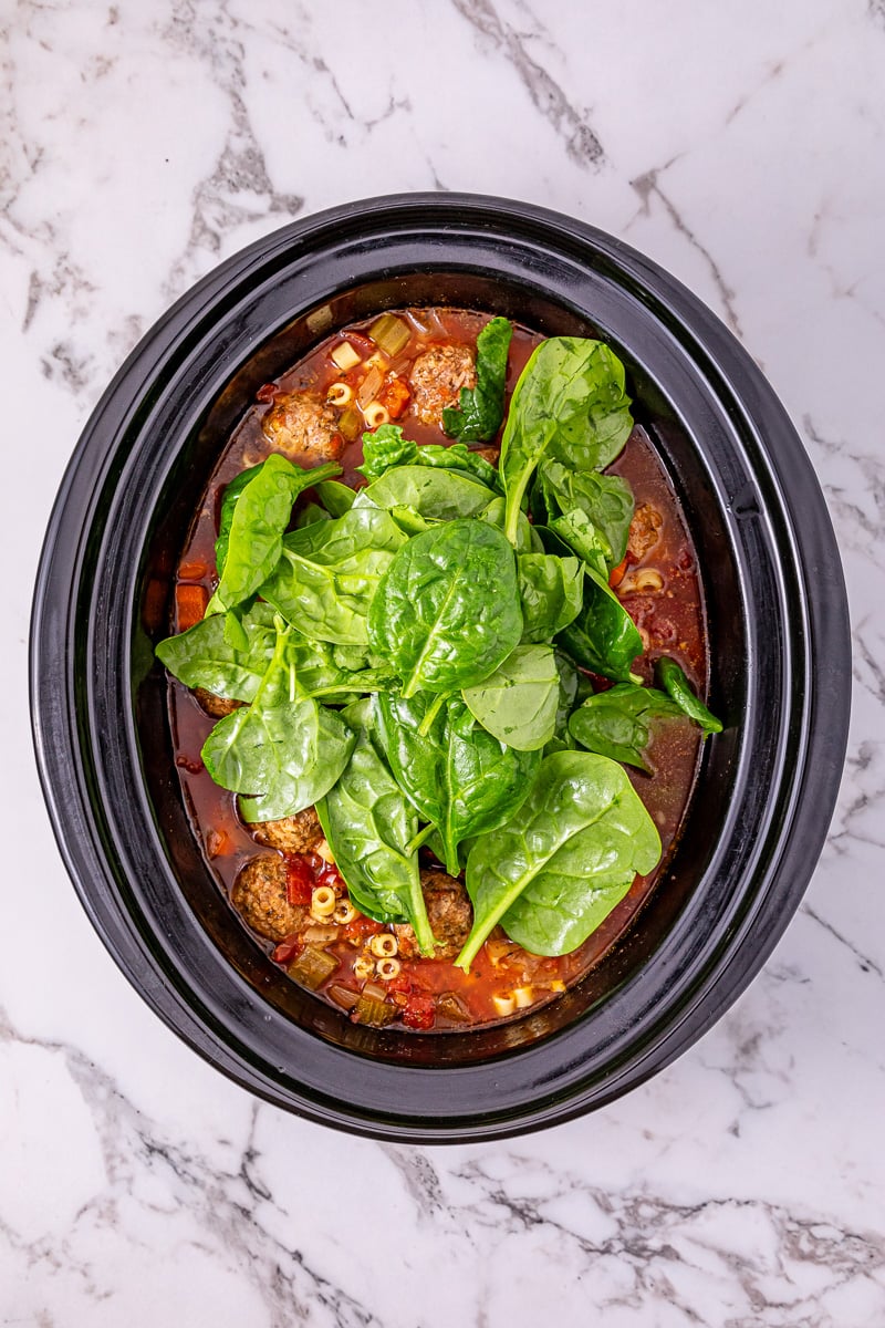 Spinach is added to the crockpot.
