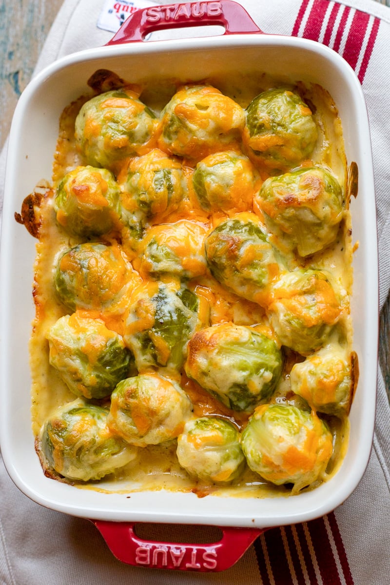 Cheesy brussels sprouts in red baking dish.