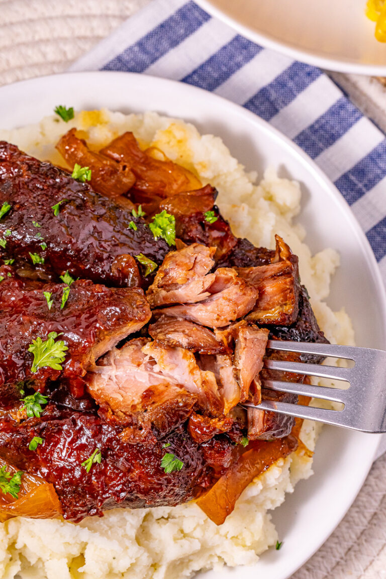 Crockpot country style pork ribs on a plate with mashed potatoes.