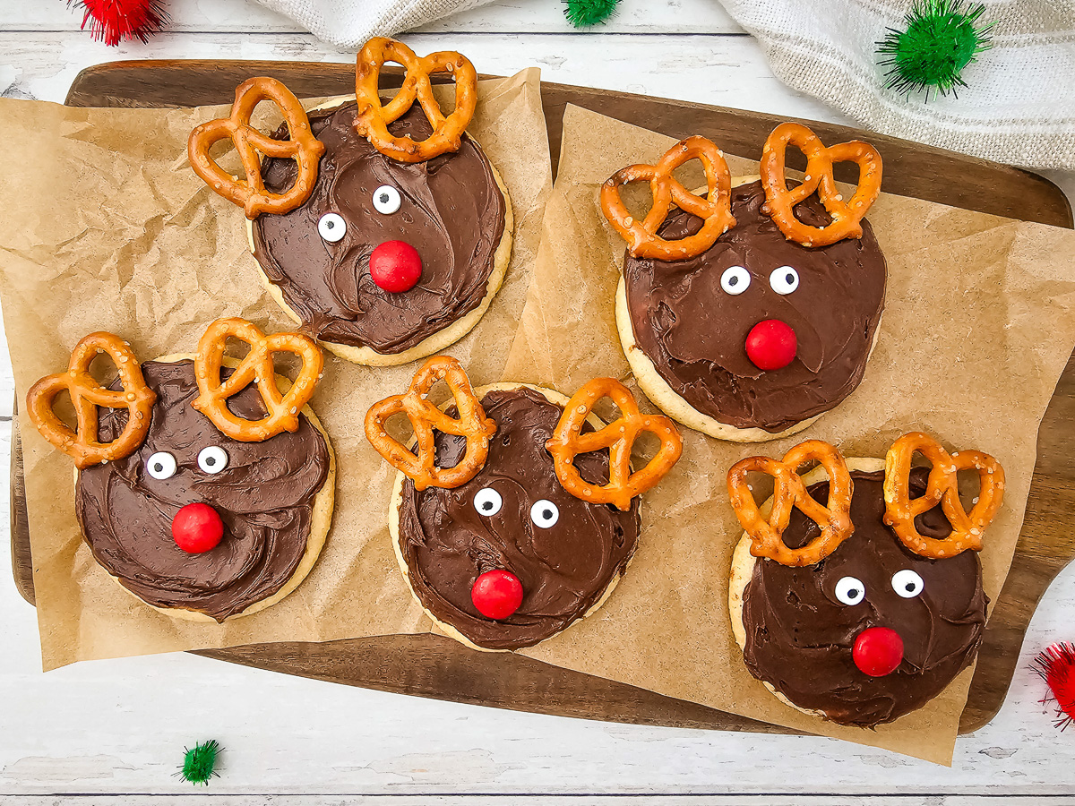 Reindeer sugar cookies on parchment lined wooden board.
