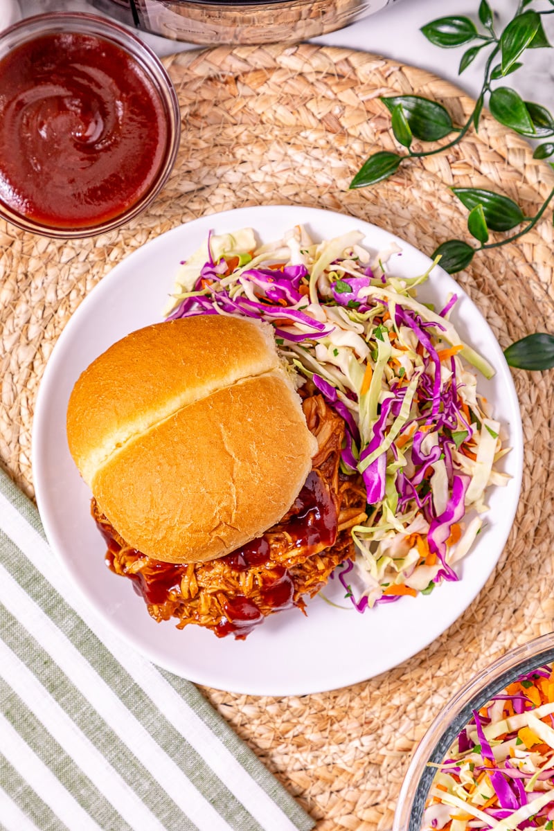 BBQ chicken served on bun with coleslaw on the side.