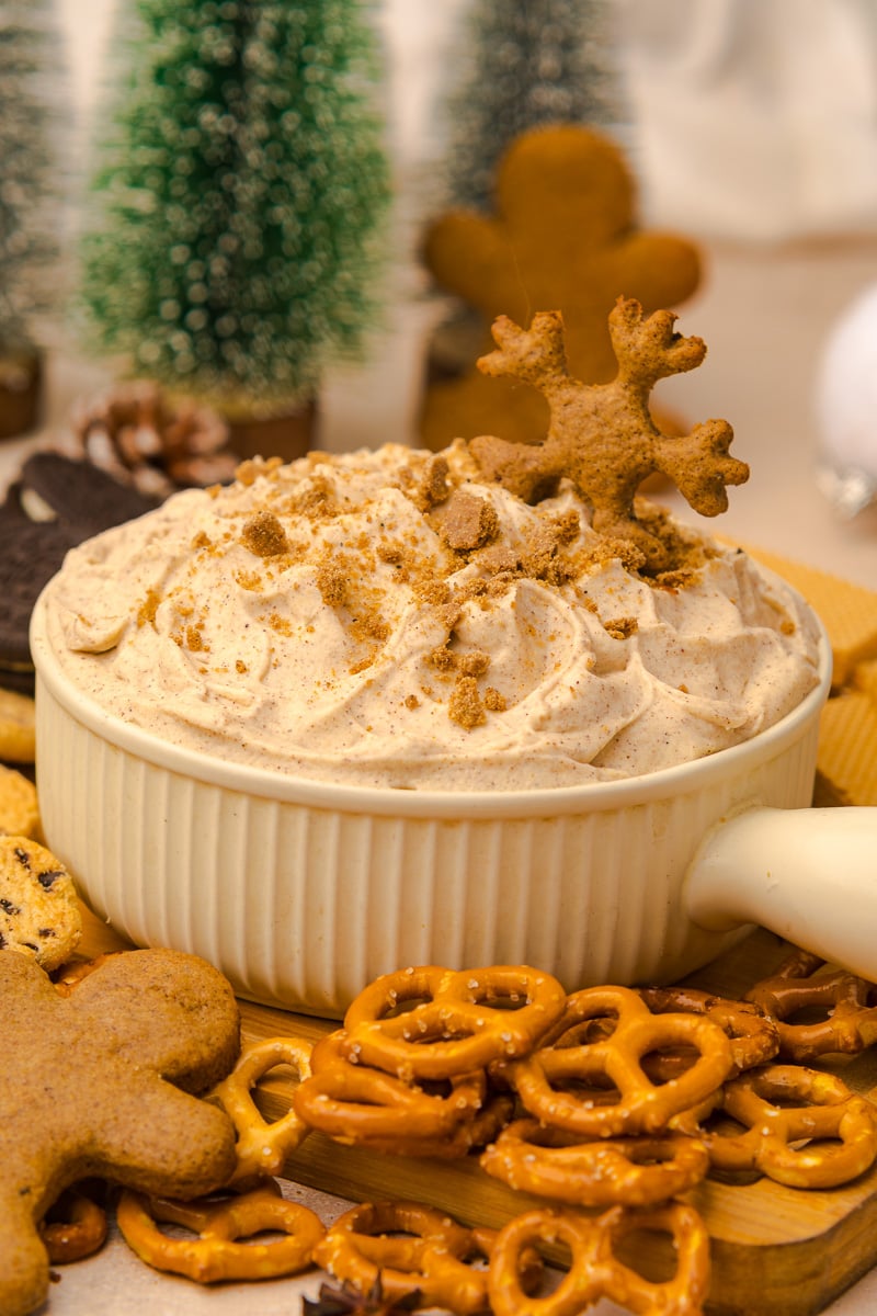 Gingerbread dip with a cookie dipped in on a board surrounded by dippers.