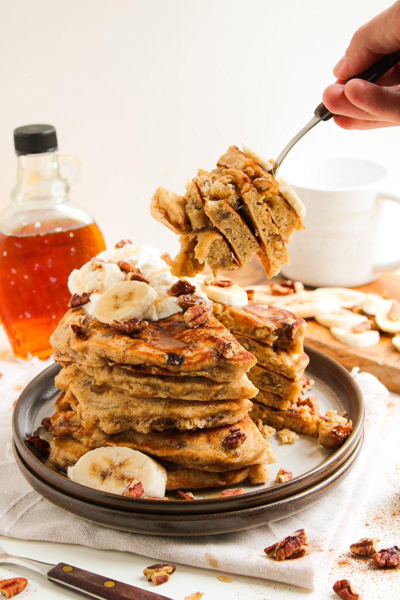 Bite of pancakes on a fork held over the stack of pancakes.