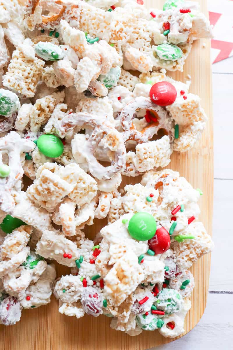 Christmas Chex mix with M&M's on a wooden board.