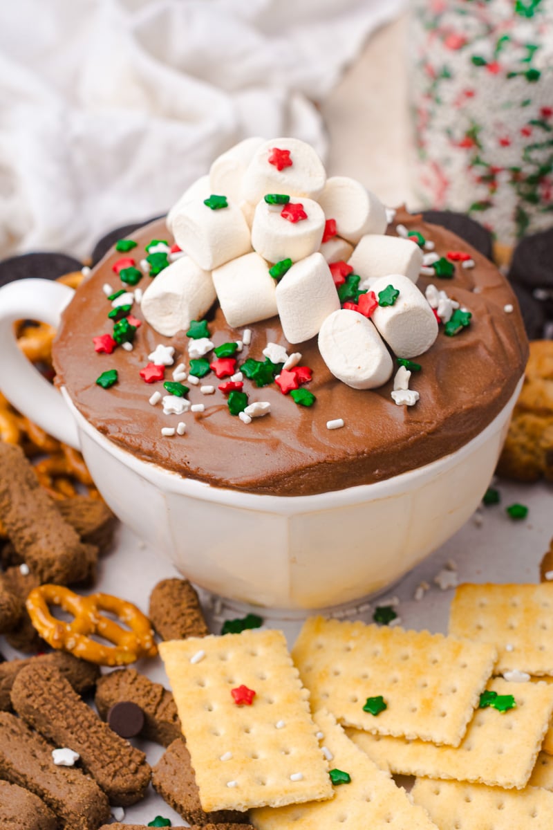 Hot cocoa dip in bowl with mini marshmallows and holiday sprinkles.