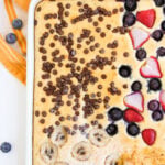 Baked sheet pan pancakes overhead view with various toppings.
