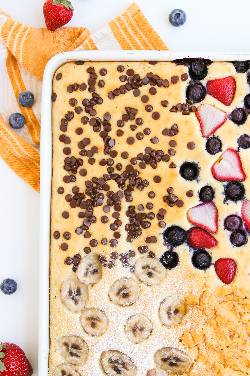 Baked sheet pan pancakes overhead view with various toppings.