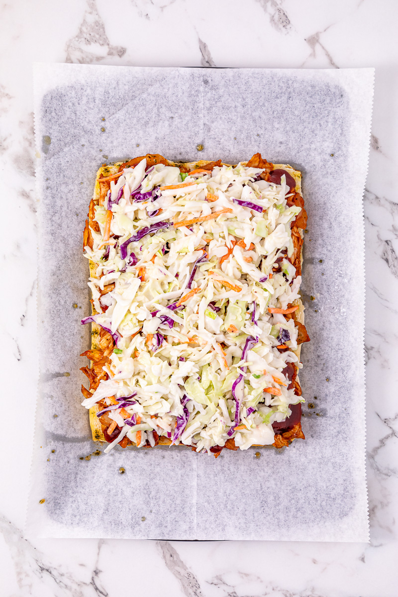 Coleslaw is added to the top of the chicken mixture on hot sliders.