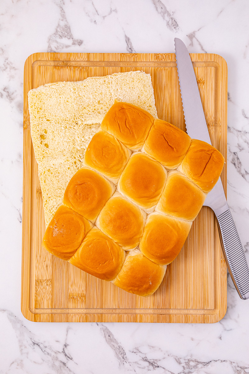 Sliced slider buns on wooden board.