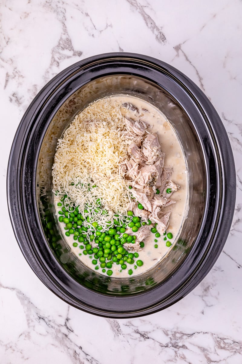 Parmesan cheese and peas are added to the top of the crockpot.