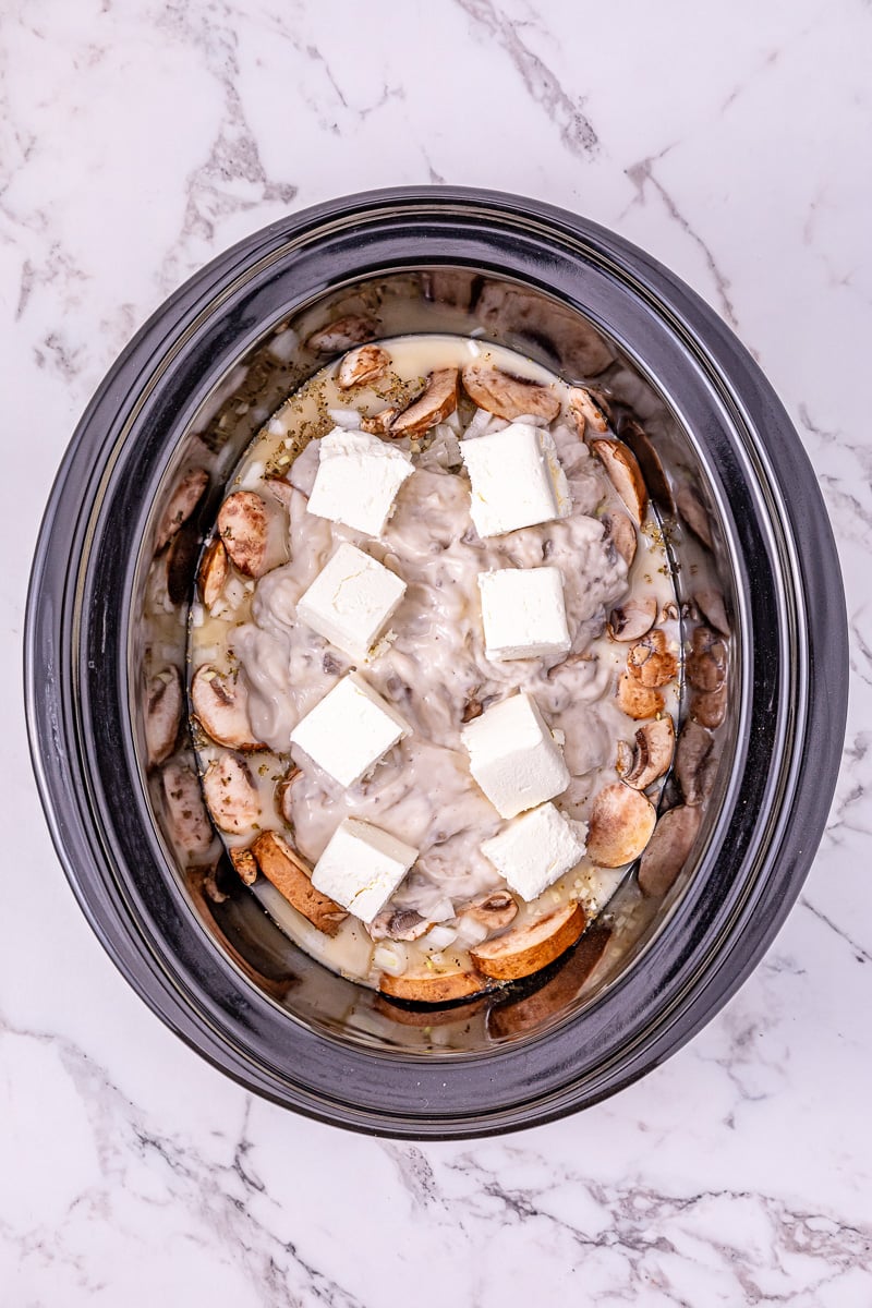 Cubed cream cheese is placed on top of the turkey tenderloins in crockpot.