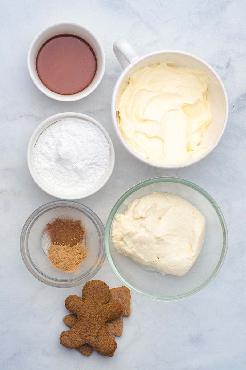 Ingredients for gingerbread cheesecake dip laid out in small bowls on counter in preparation for the recipe.