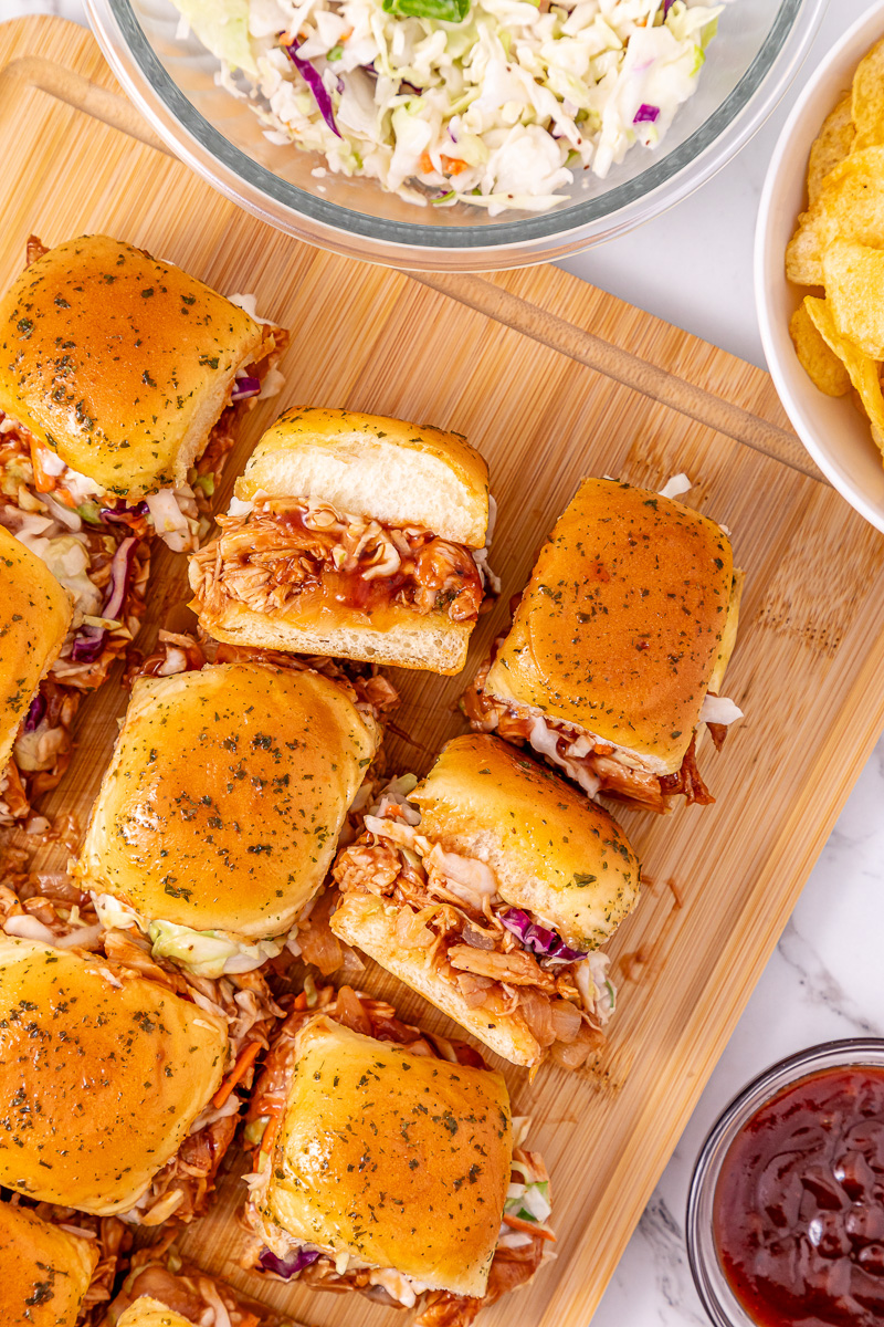 BBQ chicken sliders placed on a wooden cutting board.
