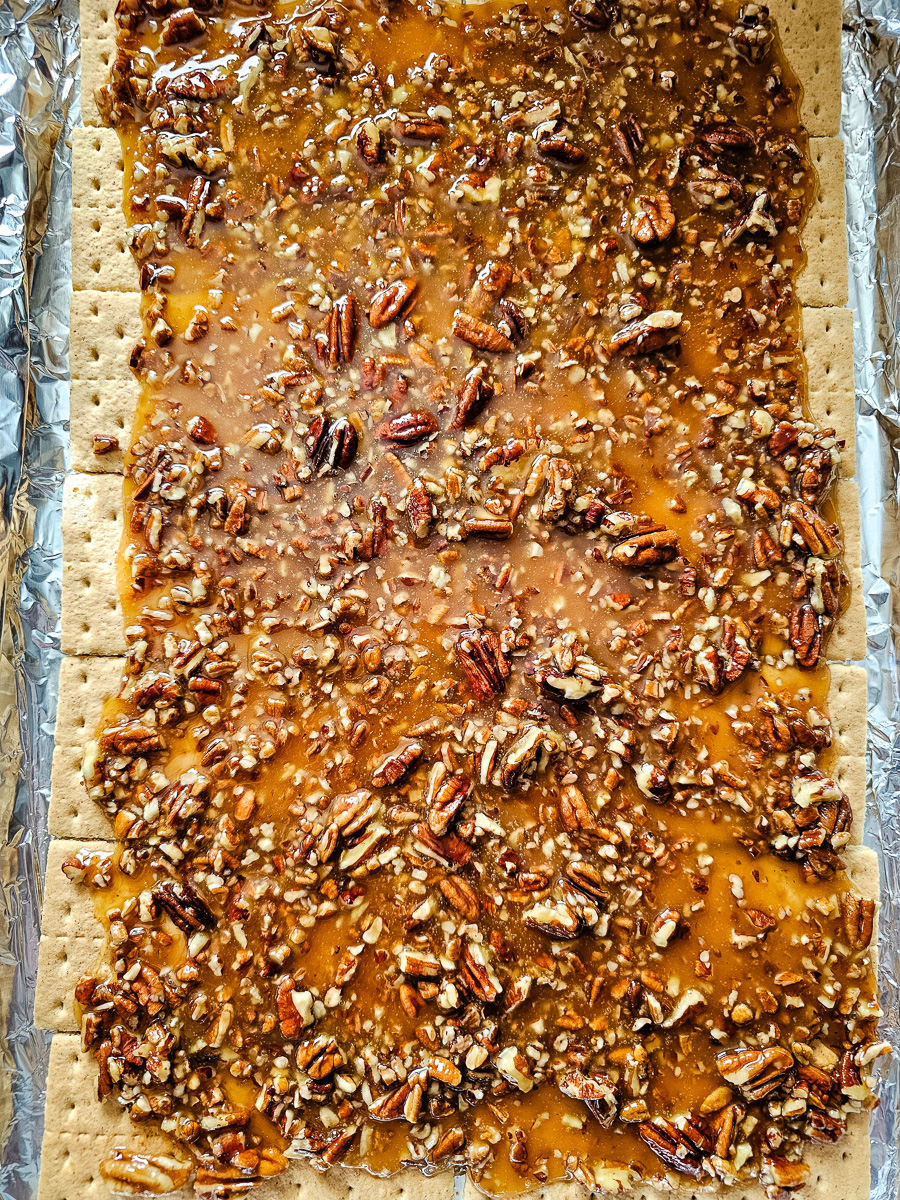 Pecan and butter mixture is sptread on top of Graham crackers.