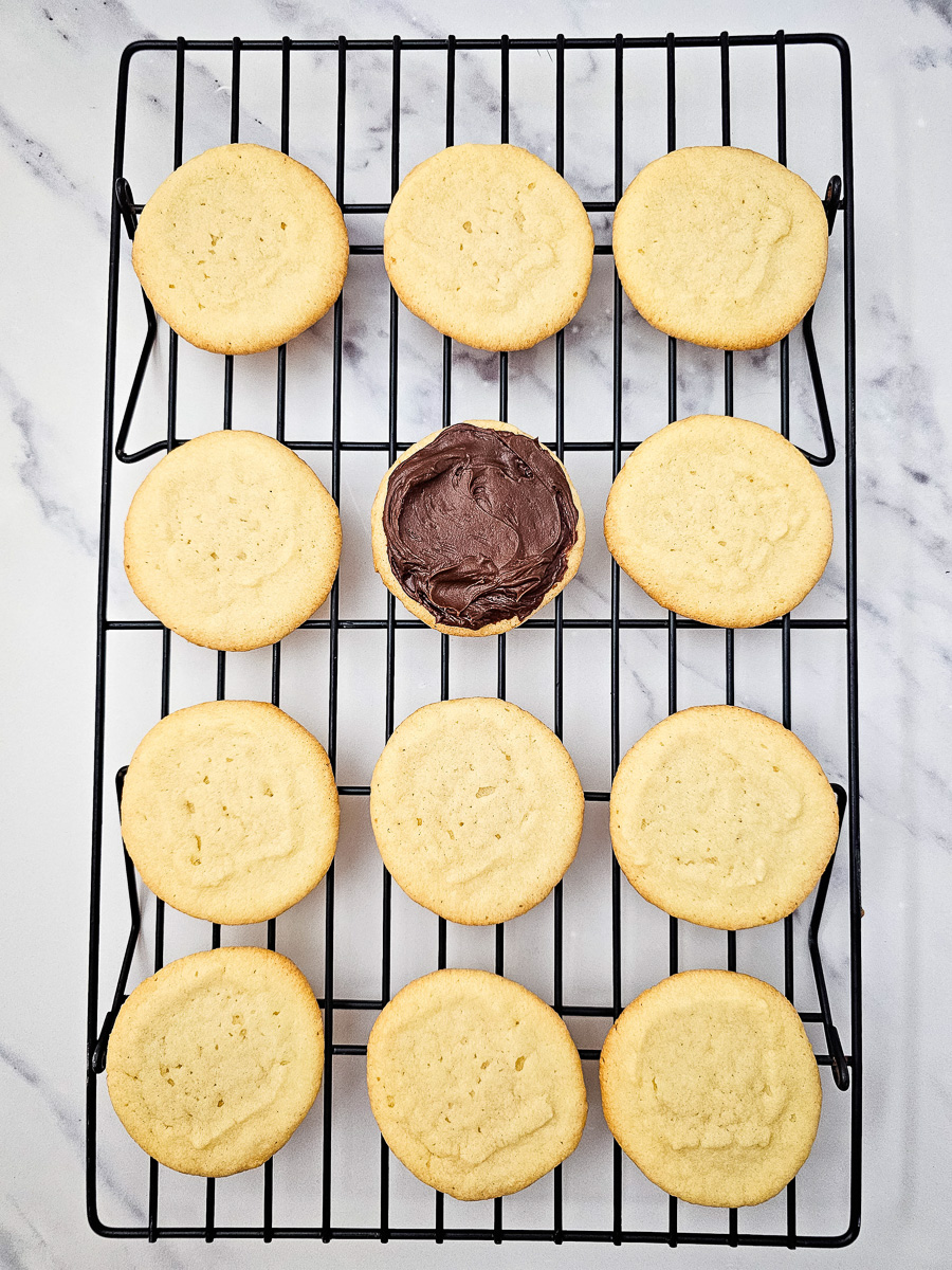 Chocolate frosting is added to the tops of the baked sugar cookies.