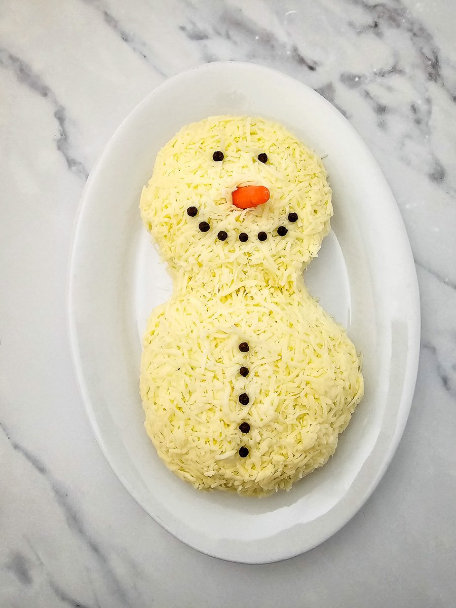 Peppercorns are used to create the eyes, mouth and buttons for the snowman.