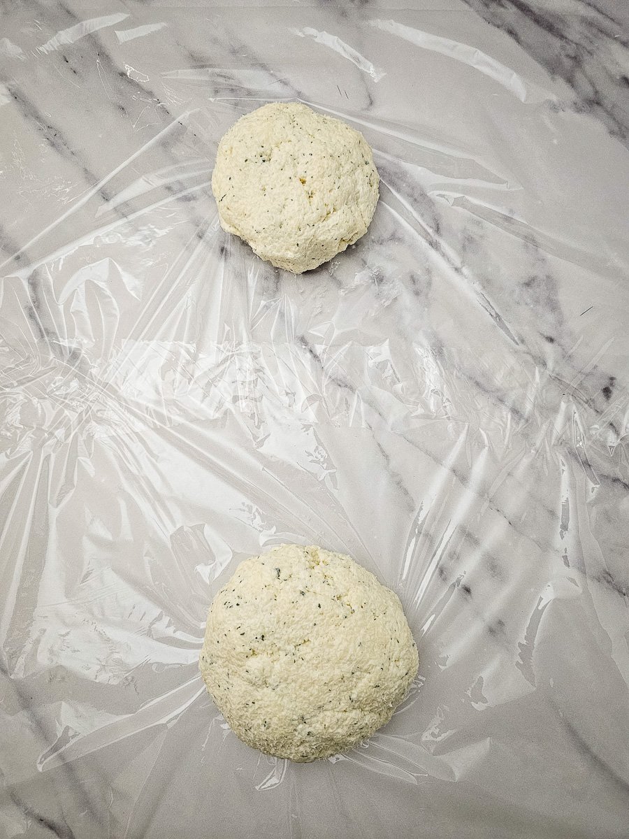 Cream cheese mixture is shaped into balls and flattened into disks on parchment paper.