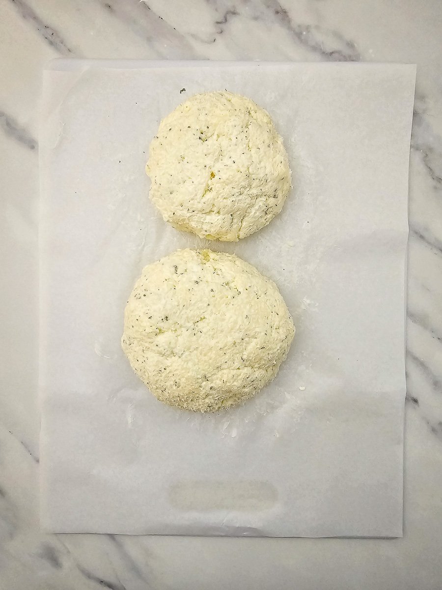Chilled cheese balls is placed on pachment paper gently touching each other.