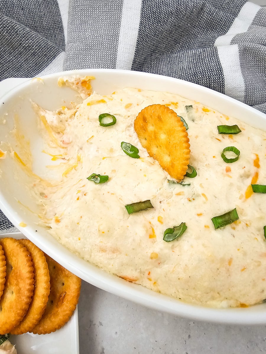 Hot seafood dip in glass bowl with crackers on the side.