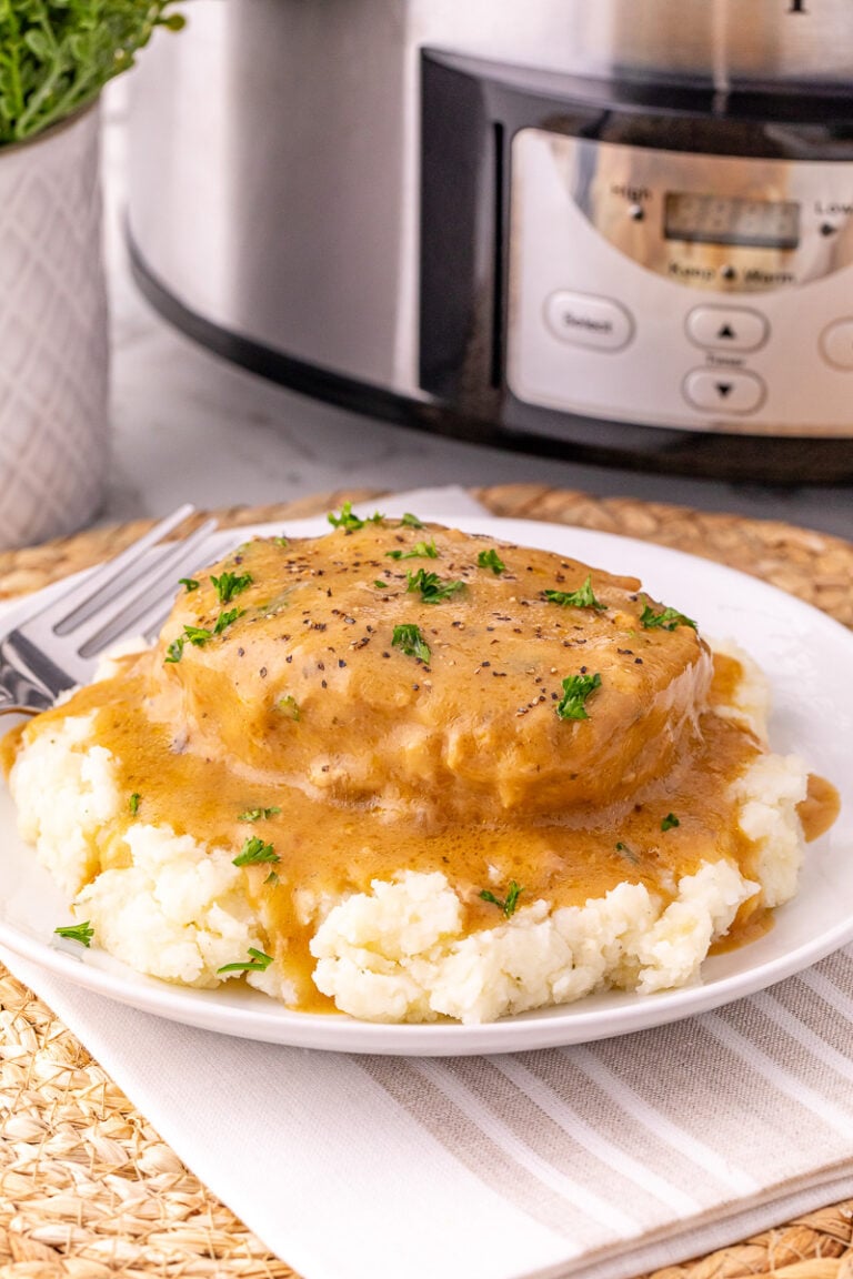 Creamy ranch pork chops on bed of mashed potatoes on plate.