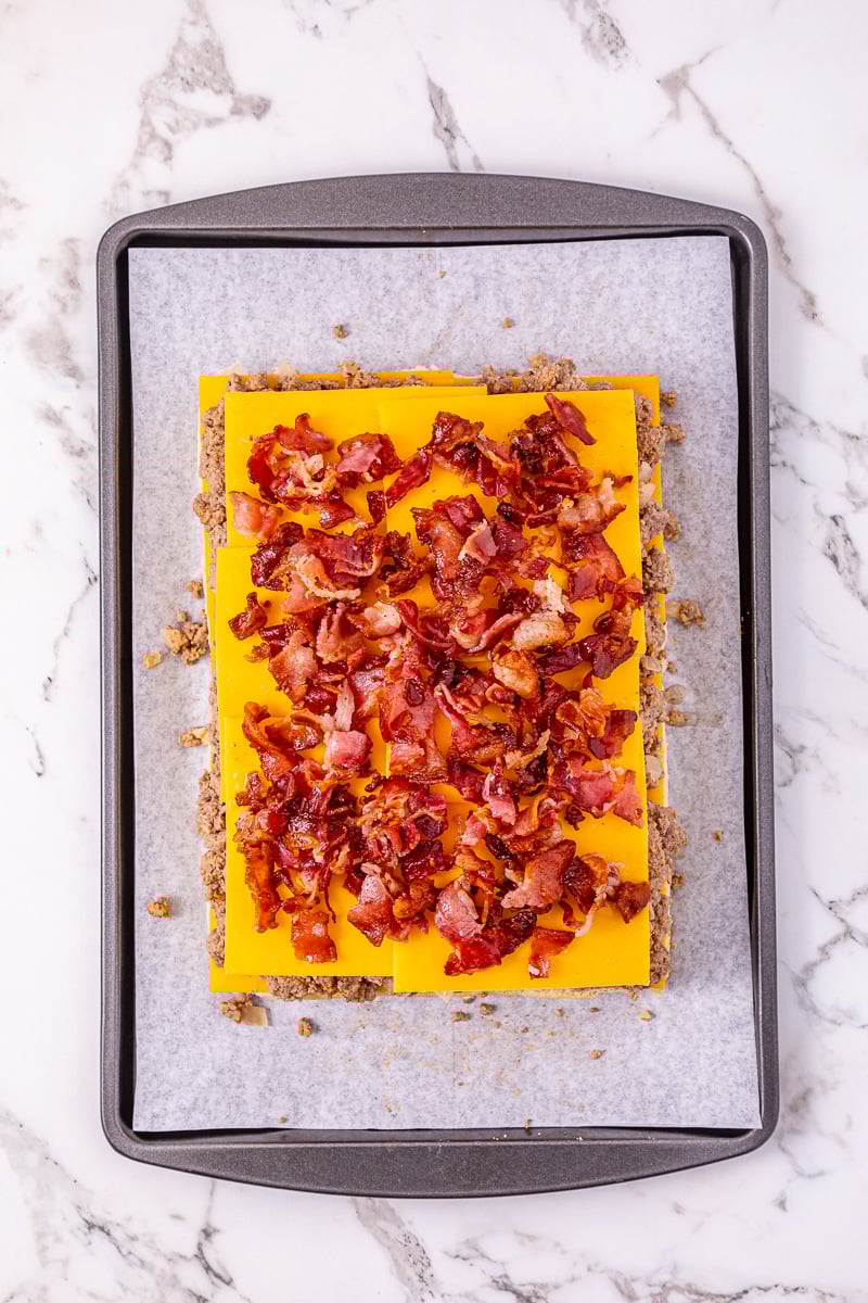 Bacon is sprinkled on top of cheese.