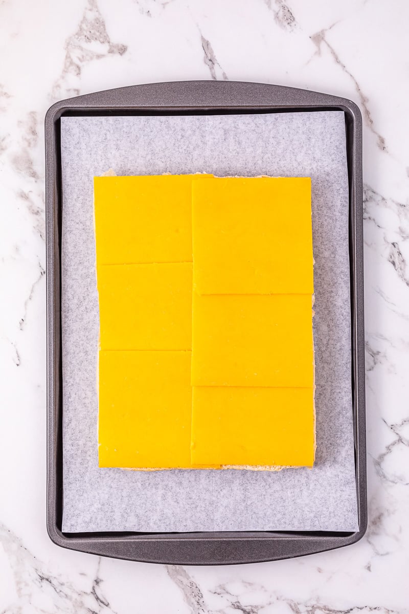 Slices of cheddar cheese placed on the bottom of slider buns.